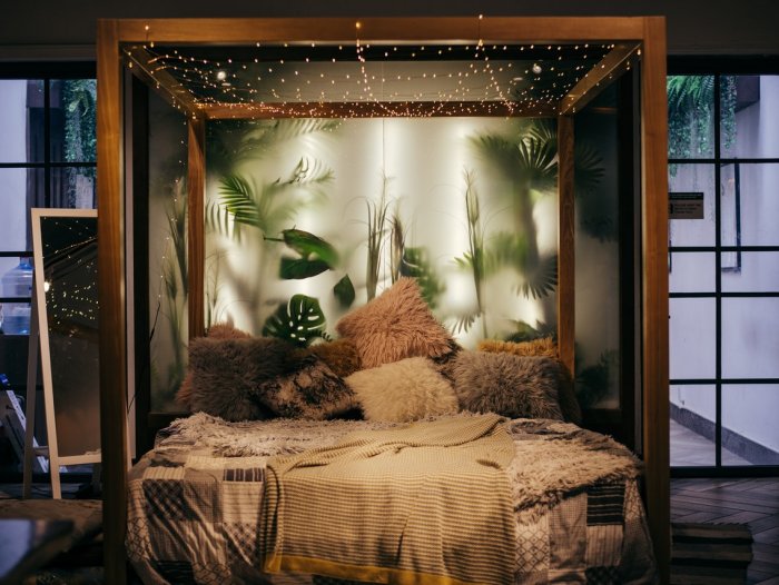 Warmly lit bed with fairy lights and window behind it