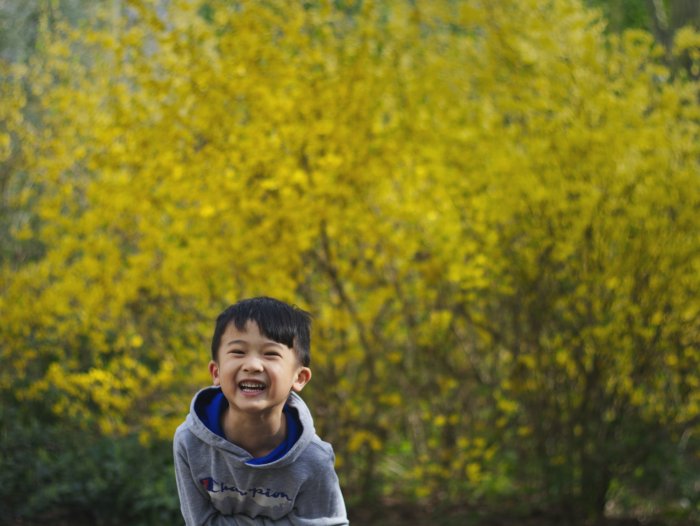 Boy smiling at camera, greenery behind him