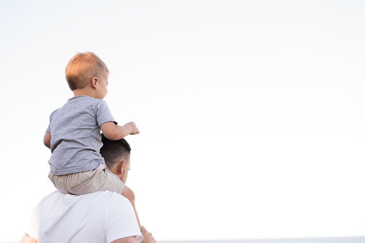 father with his son on his shoulders outside