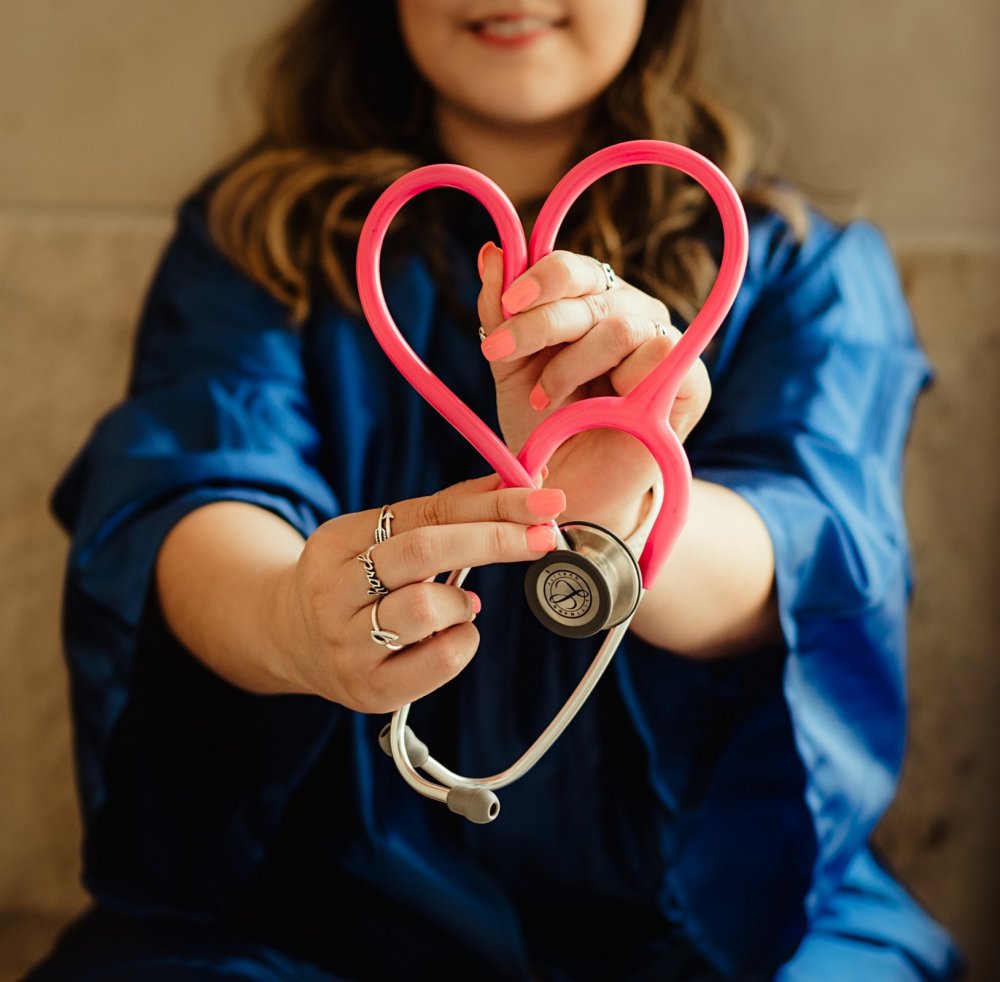 Woman holding stethoscope in the shape of a love heart