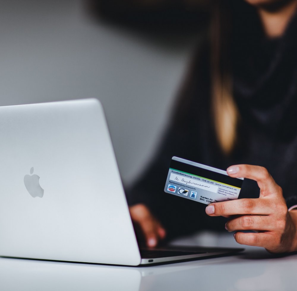 Woman holding credit card and looking at laptop