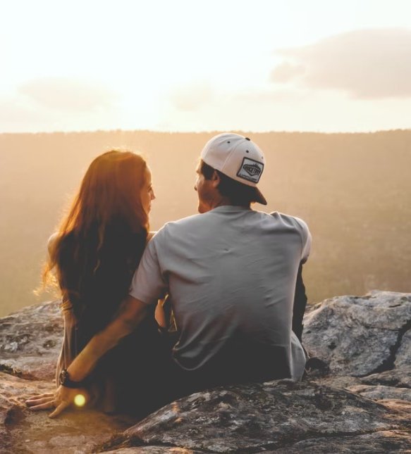 Couple smiling at each other, mountains in front of them