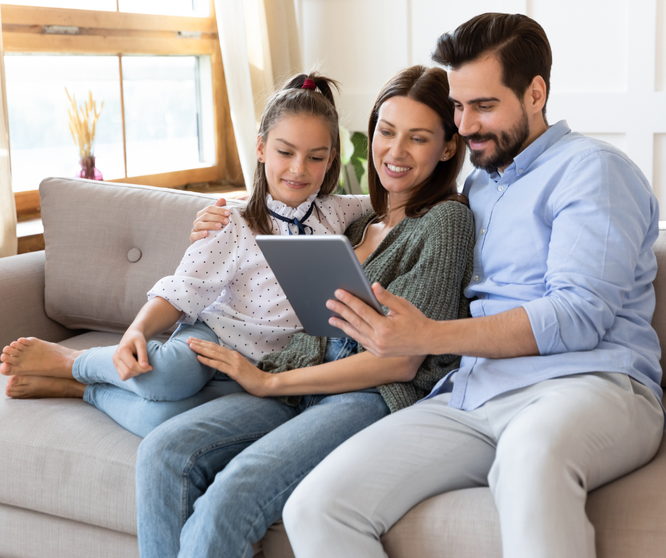 A young family smile while conducting a video call on a tablet