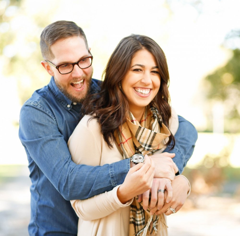 A young couple smile while hugging each other